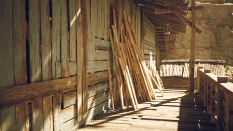 Sunlit wooden structure with stacked beams in a rustic setting