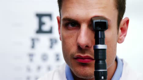 primer plano del optometrista mirando a través del oftalmoscopio