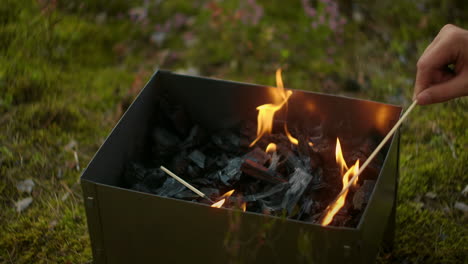 flame-in-chargrill-person-is-mixing-coals-detail-view-slow-motion-shot-camping-and-picnic-at-nature