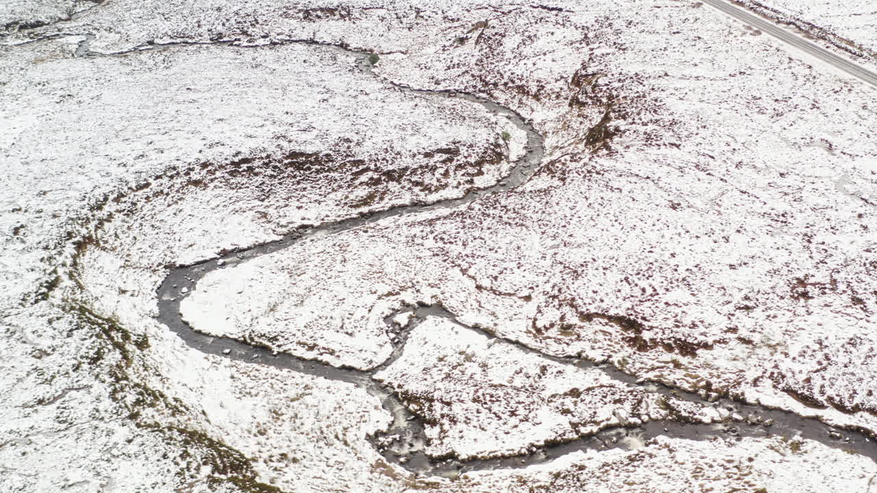 Discover the breathtaking beauty of County Donegal, Ireland, as a winding river flows through a serene winter landscape covered in snow and frost.