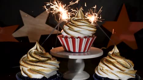 bengalas que explotan alrededor de cupcakes rojos, blancos y azules con la parte superior de remolino de merengue tostado