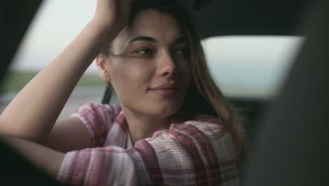 young woman looking out of the window's car while having a road trip