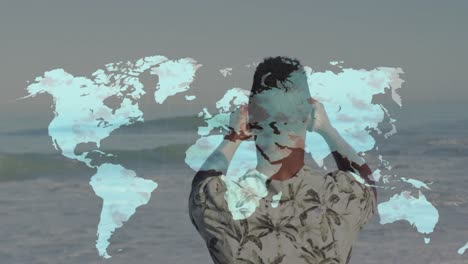World map over rear view of african amerian man taking pictures from his smartphone at the beach