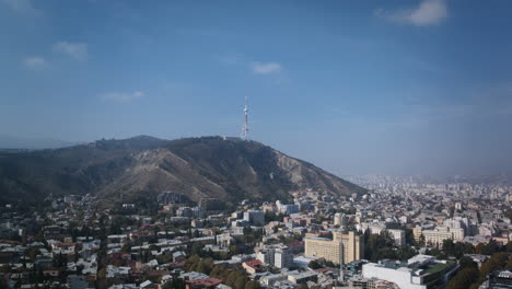 hiperlapso aéreo durante el día sobre la ciudad de tbilisi, georgia centrándose en la torre de televisión de tbilisi
