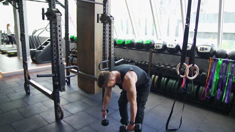 young sportsman in a modern gym. handsome athlete exercising with dumbbells. muscular bodybuilder actively training in luxury fitness club.