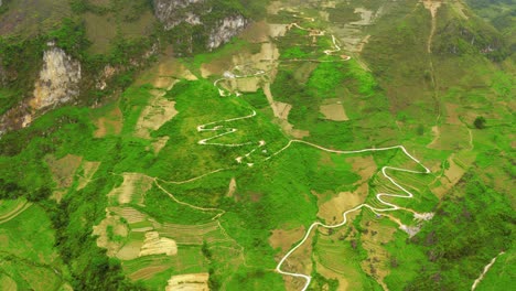 Aerial-tilt-up-revealing-a-winding-road-cut-into-the-mountains-of-the-gorgeous-Ma-Pi-Leng-Pass-in-northern-Vietnam