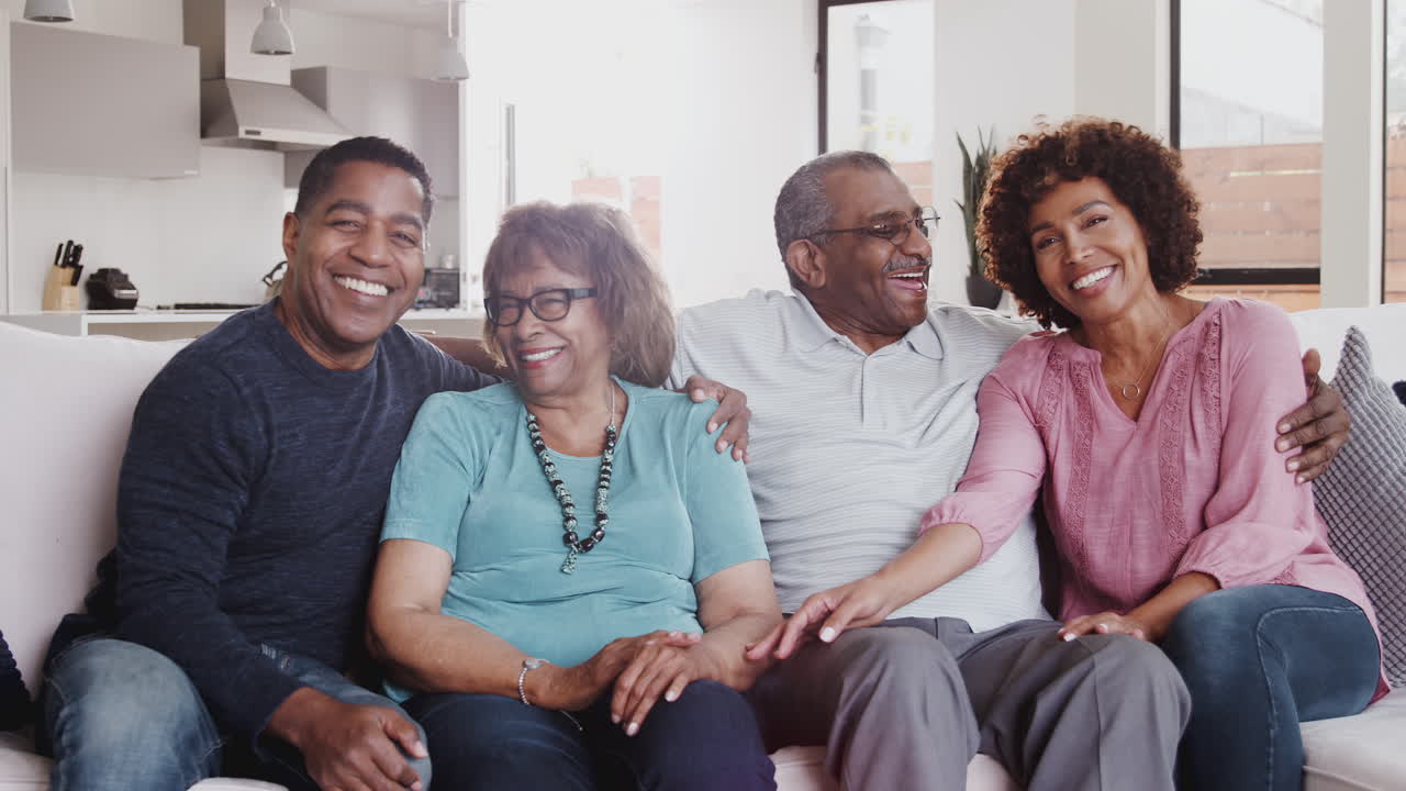 Happy middle aged black couple and parents relax sitting together at home