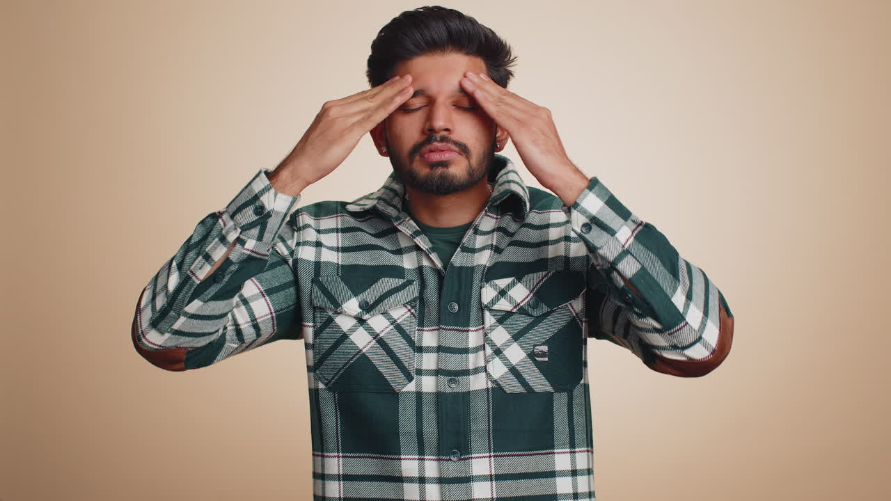 Indian man rubbing temples to cure headache problem, suffering from tension and migaine stress pain
