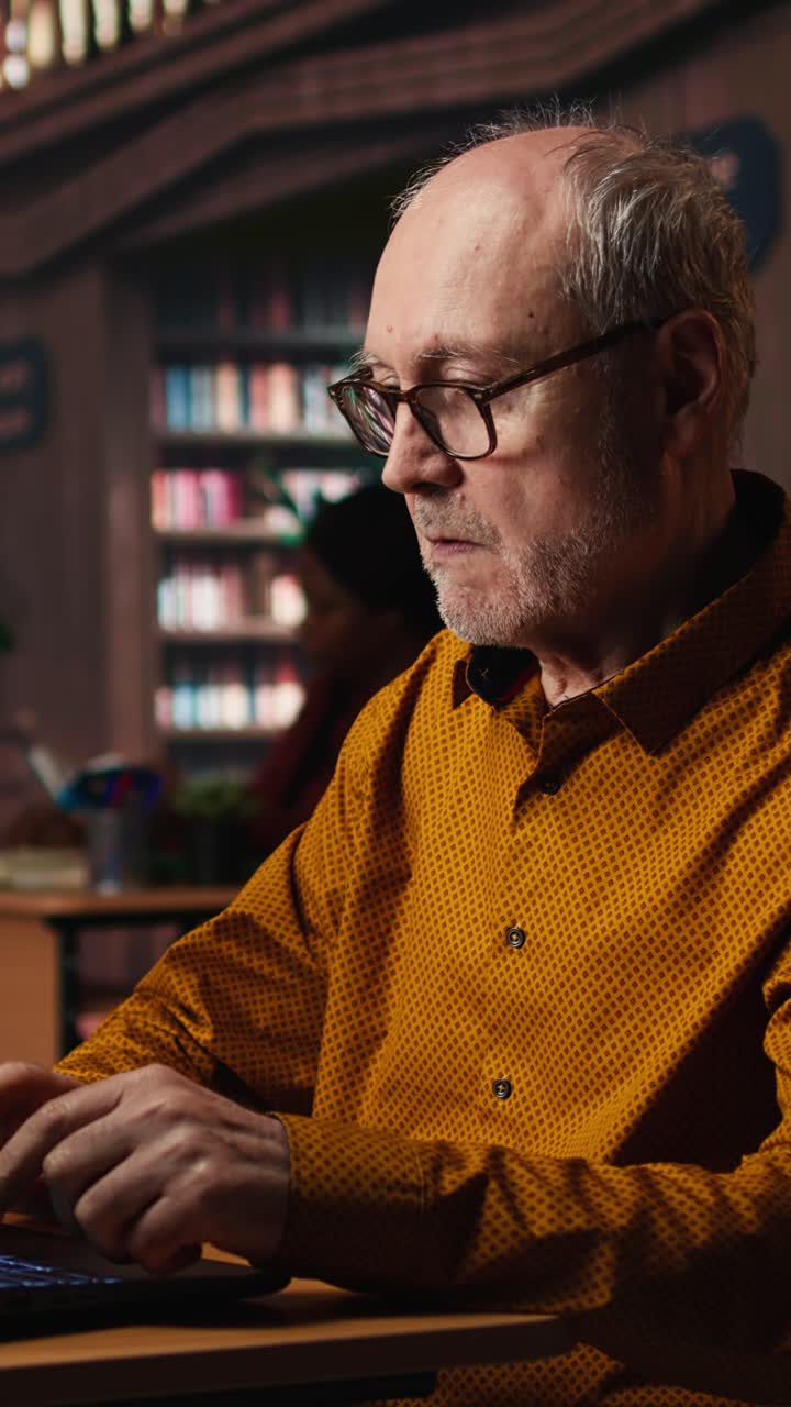 Vertical Video Focused senior guy reading academic text on laptop at the university