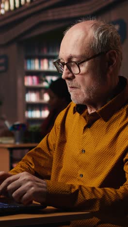 vertical video focused senior guy reading academic text on laptop at the university