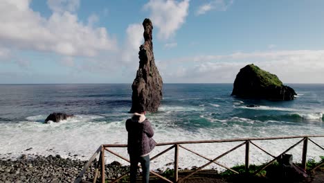 Aerial-of-photographer-walking-out-to-take-picture-of-coastal-rock-formation,-Madiera,-Portugal