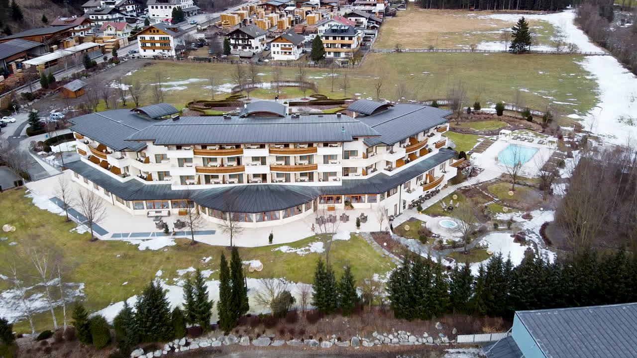 un drone se acerca a un hotel alpino de lujo y terrenos en invierno