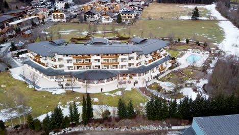 un drone se acerca a un hotel alpino de lujo y terrenos en invierno