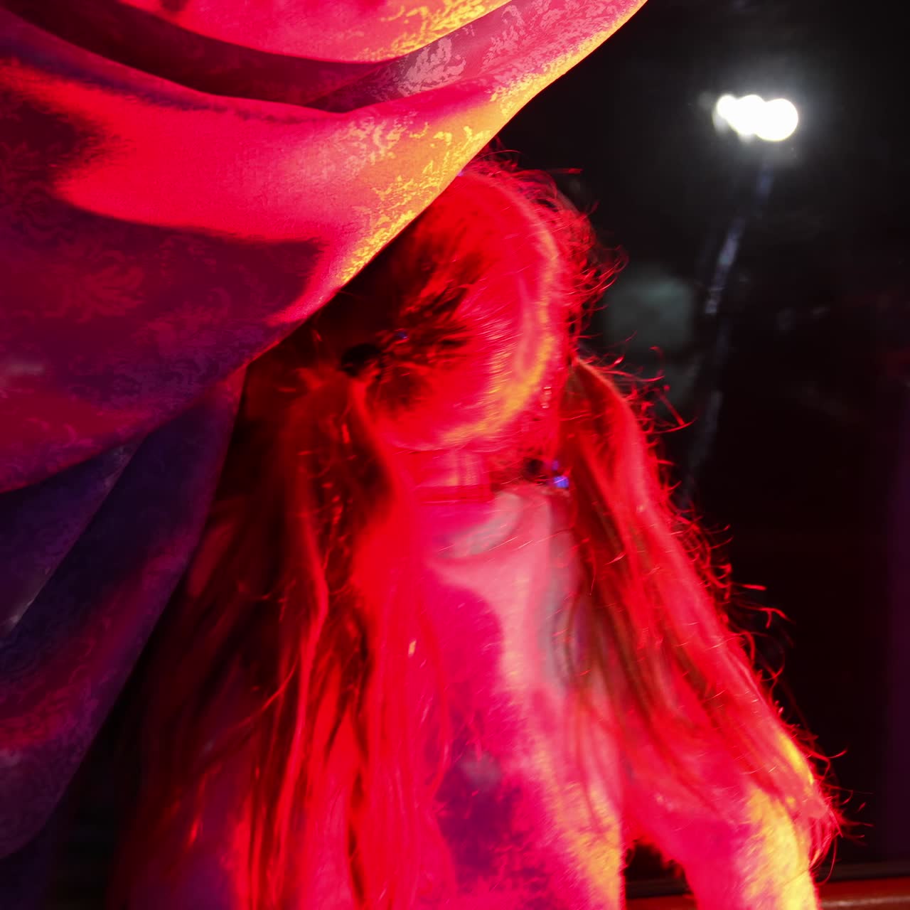 Little girl waiting for Santa Claus. Girl looks out the window during winter evening near the Christmas tree