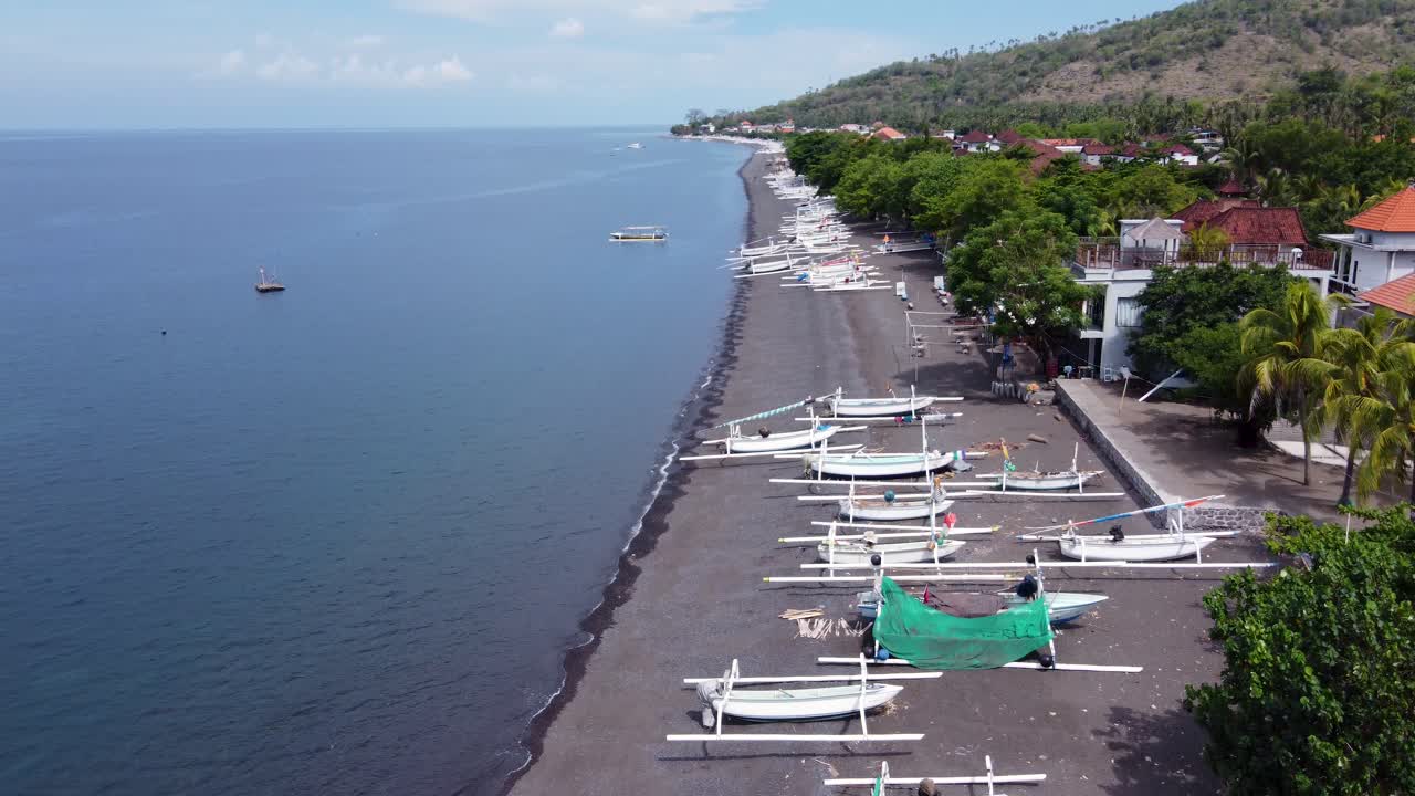 White jukung canoe fishing boats with outriggers on volcanic black sand beach of Amed Village in Bali, Indonesia