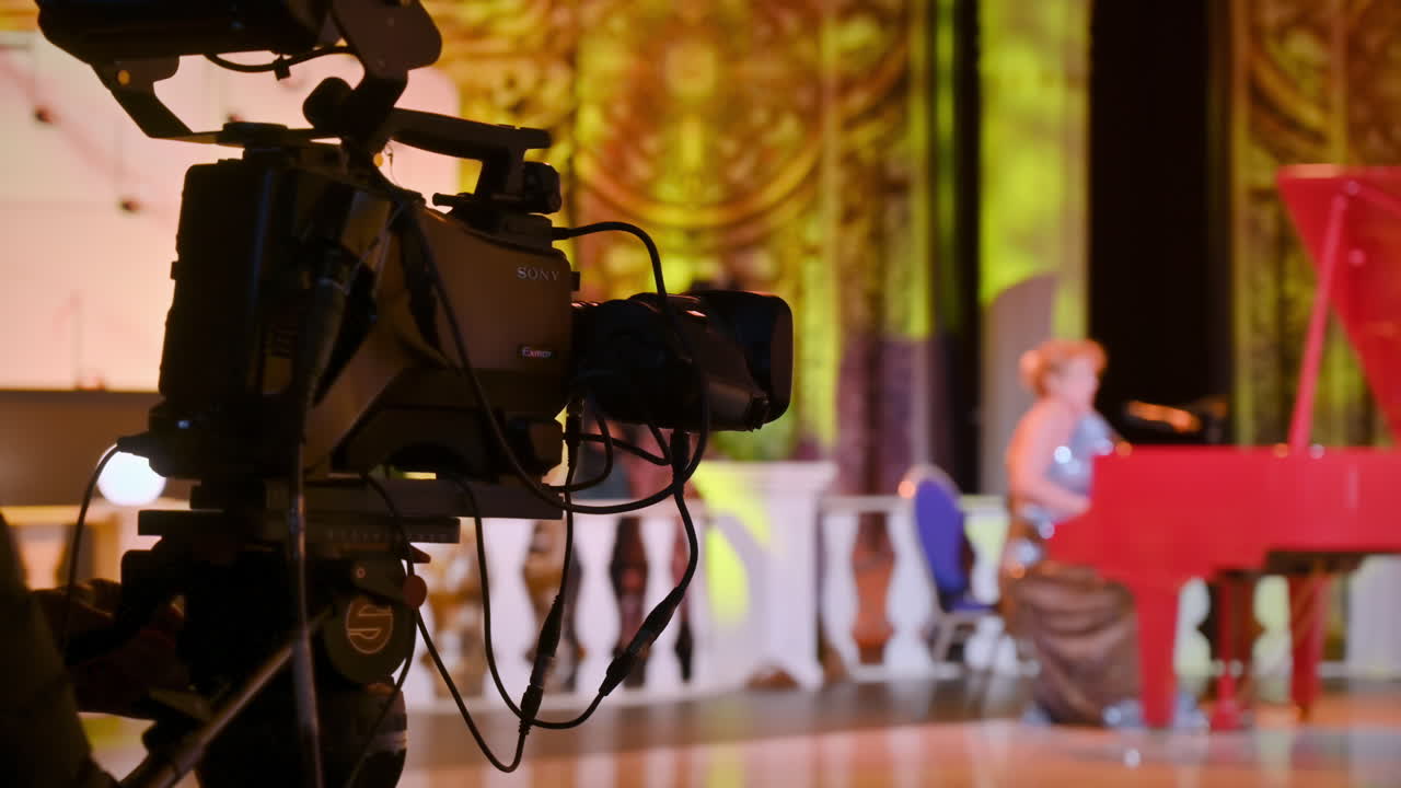 Professional camera filming a woman playing the piano on the backstage of a TV set