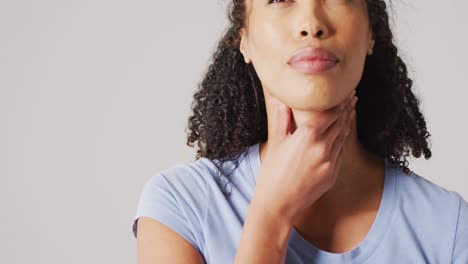video de una mujer biracial tocando su cuello sobre un fondo blanco