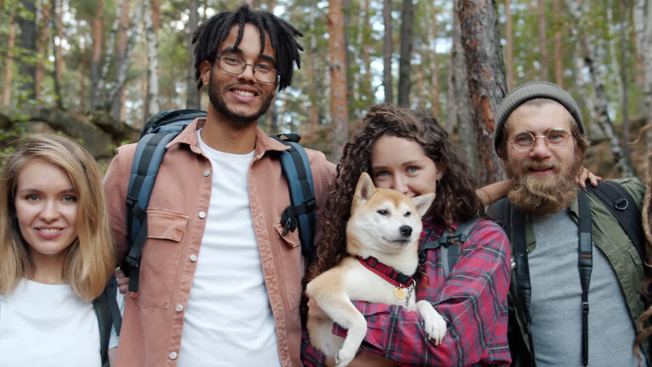 Happy friends hiking in the forest with a dog