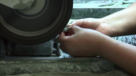 detail of the hands of a worker grinding a jade gemstone, jade factory, antigua guatemala, central america