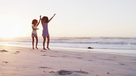 madre y hija afroamericanas divirtiéndose caminando juntas en la playa