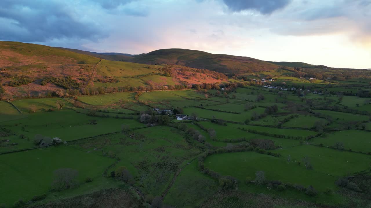 las imágenes aéreas de drones revelan un vasto paisaje agrícola que se extiende bajo un cielo nublado al atardecer en inglaterra, reino unido, proyectando un brillo cálido sobre los campos, creando una escena rural serena y pintoresca.