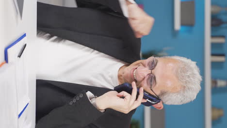 vertical video of home office worker man getting good news on the phone.