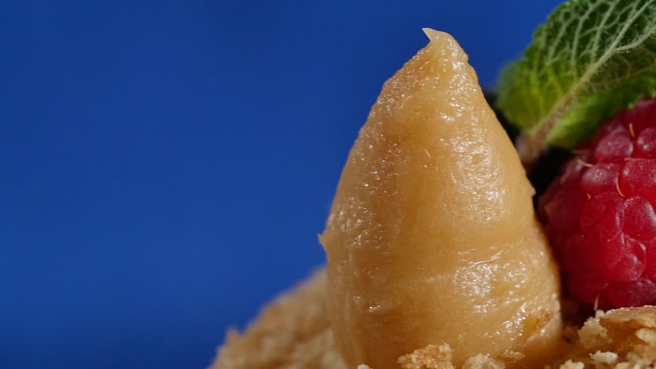 primer plano de un postre con crema, frambuesas, menta y arándanos