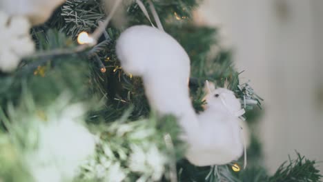 toy squirrel hangs on christmas tree with fairy lights