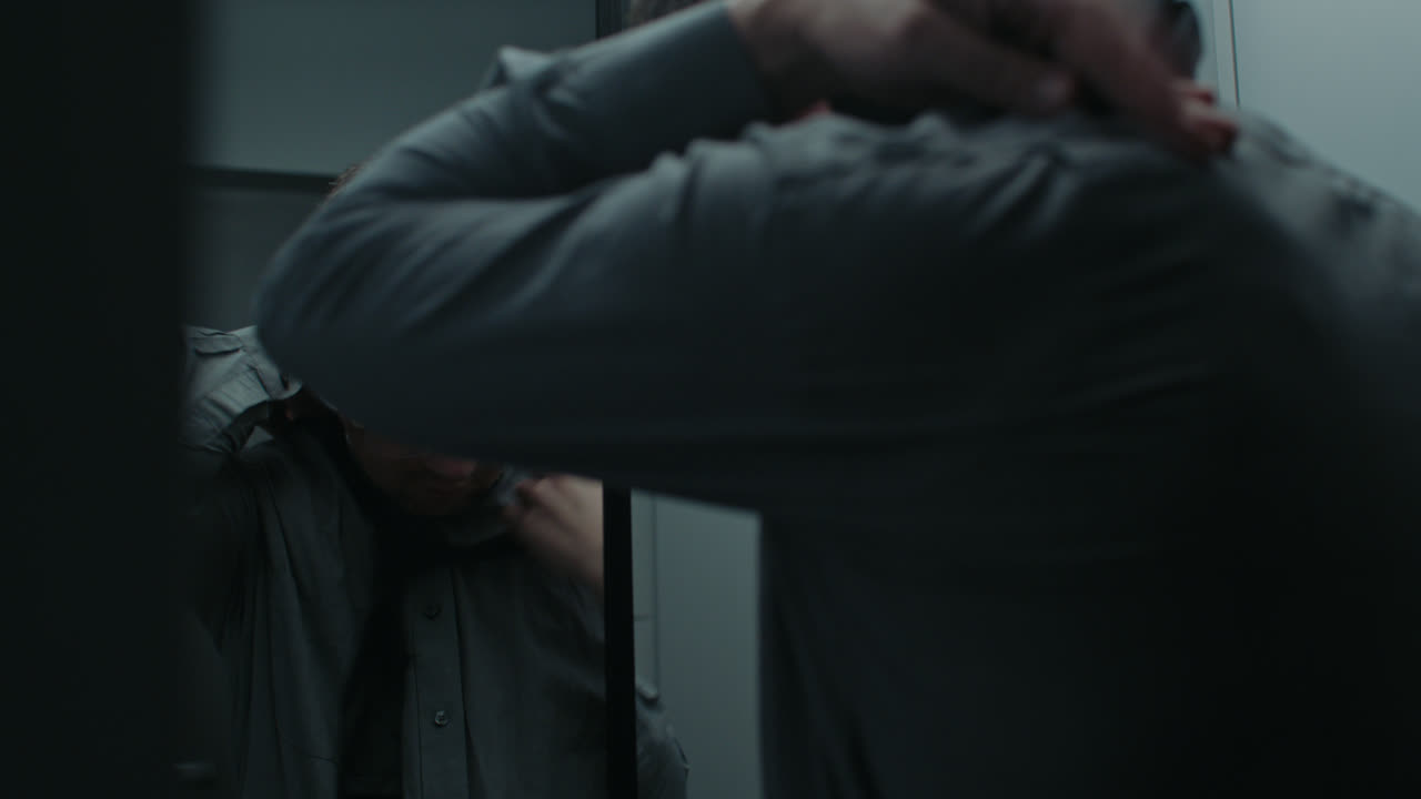 A sad man puts on his tie