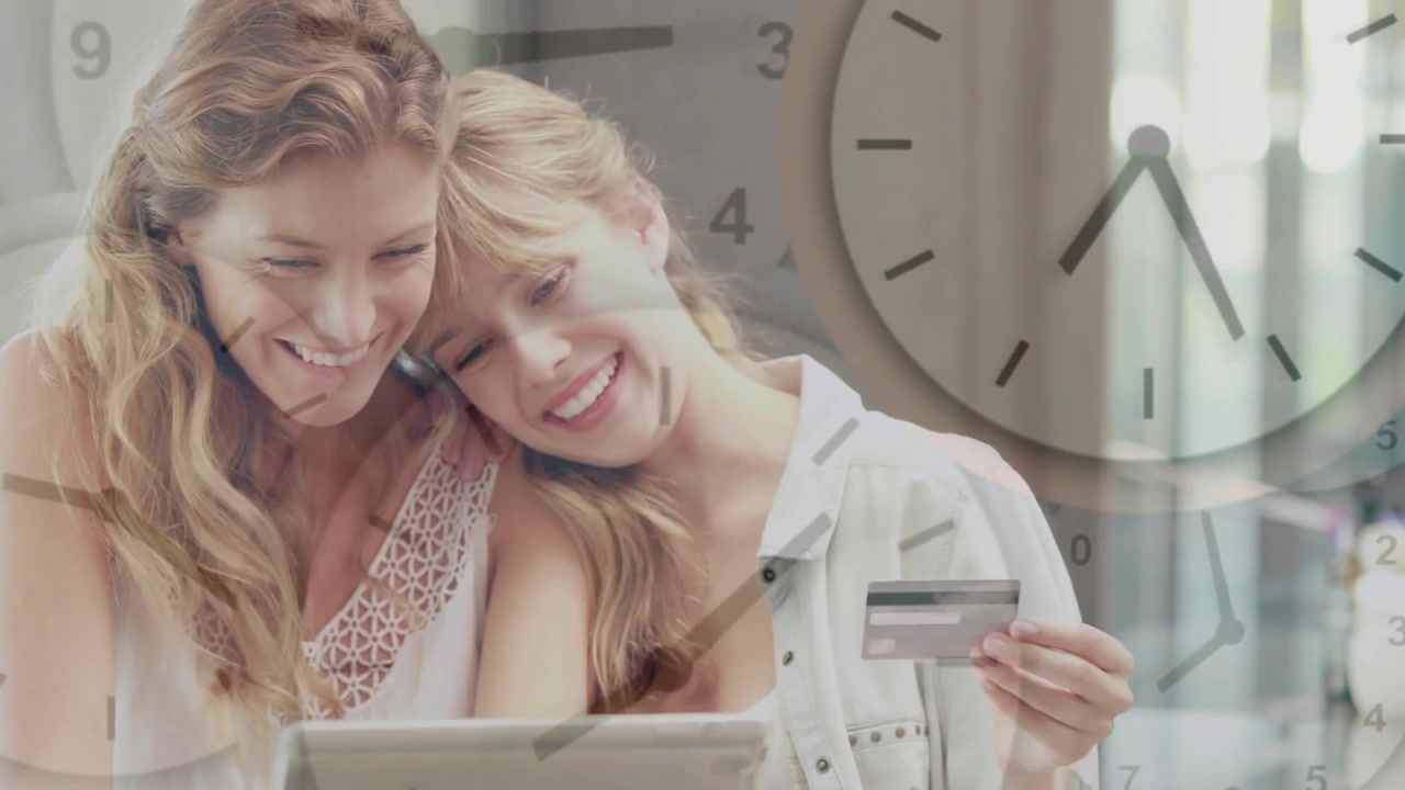 Two women tapping tablet while holding credit card, completing finance checkout with clock overlay