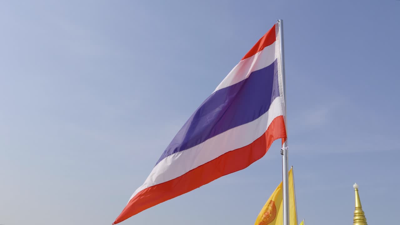 Slow motion tilt down from Thai flag to Bangkok panorama