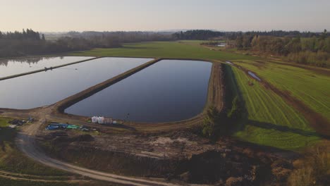 Aufsteigende-Antenne-über-Landwirtschaftlichen-Feldern-Und-Wassereinzugsgebieten,-Die-Den-Himmel-Reflektieren