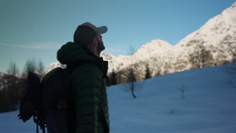 Hiker-rests-and-looks-up-at-snowy-alpine-peak,-Campagneda,-Italian-Alps