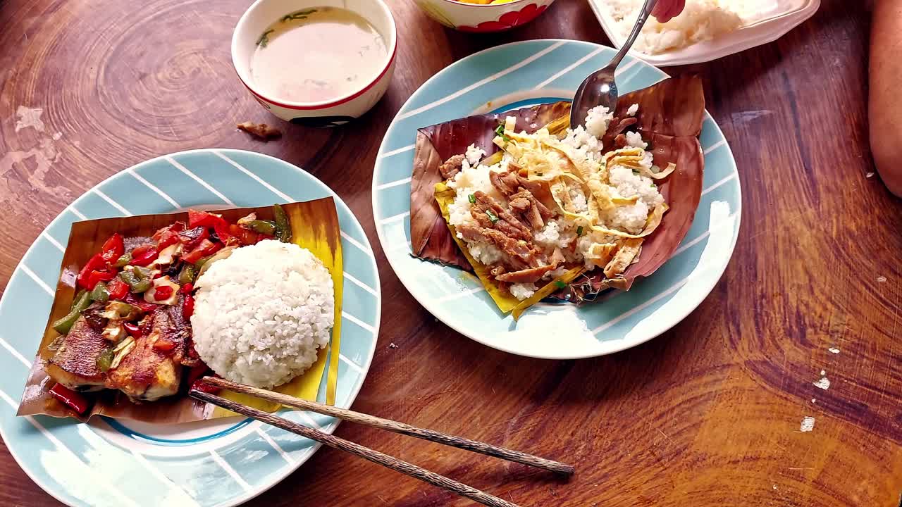 Overhead view of eating authentic traditional khmer breakfast food Trei boeng kanh chhet or spicy fried fish and Bai sach chrouk or pork with steamed rice