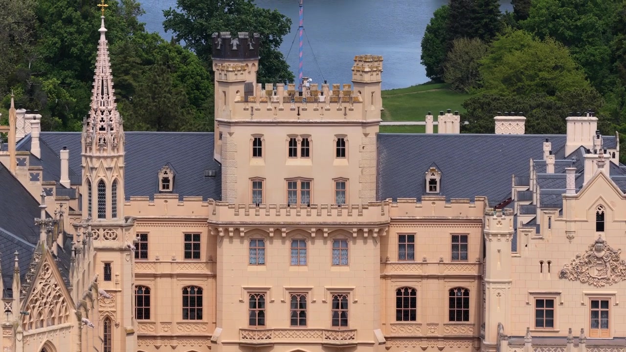 Luftfoto med drone av den nygotiske fasaden og kapelltårnet til Lednice slott i nærbilde, omgitt av vårtrær, Morava, Tsjekkia