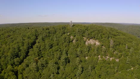 drone shot approaching lookout tower on hilltop in the middle of ontario forest