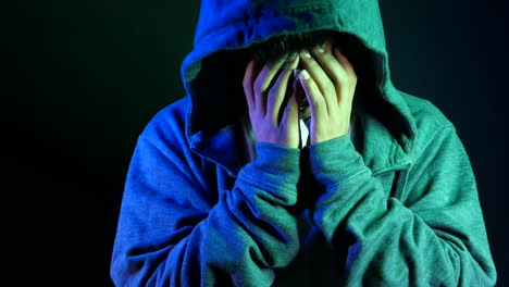 person in hoodie hiding face, expressing sadness and despair