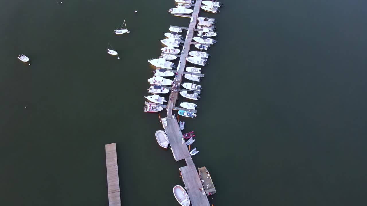 힝햄 항구 부두와 보트 위로 날아다니는 새의 눈 공중 드론, 춤추고 파티를 즐기는 사람들의 정적 드론 장면