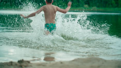 Cute-boy-with-swimwear-and-goggles-run-into-the-lake-and-swims