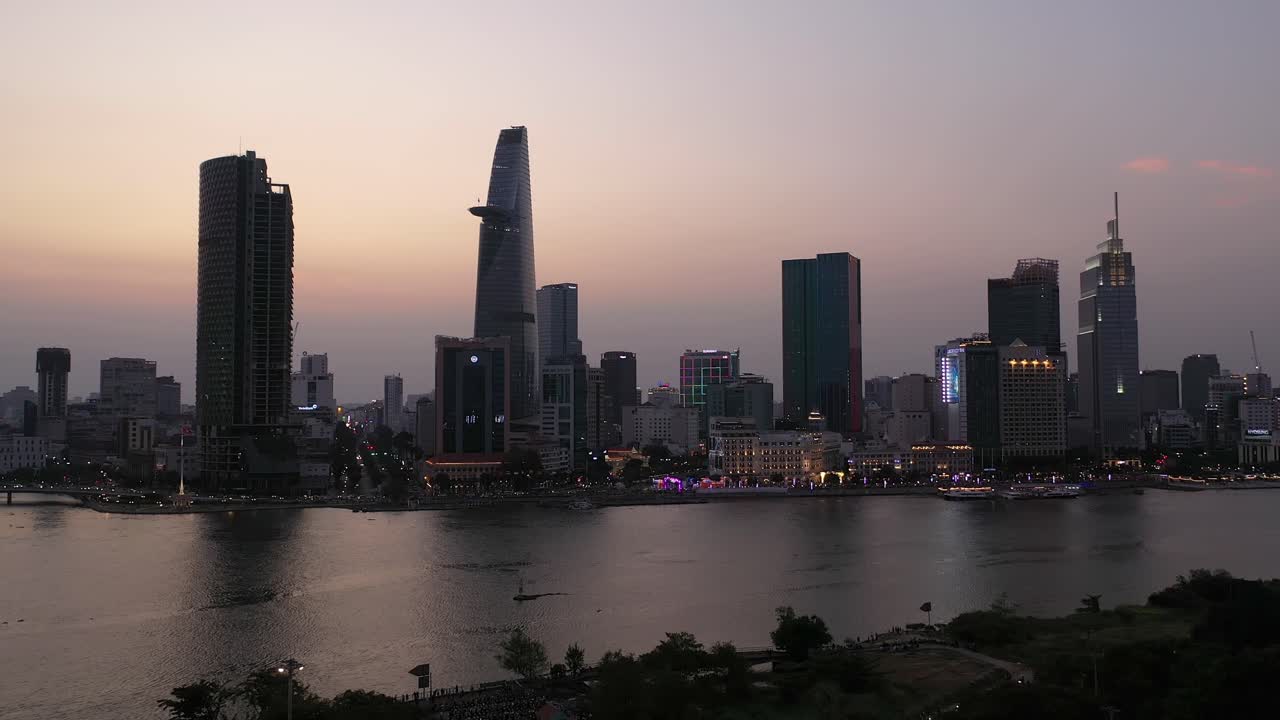 Yoğun bir akşamda, tüm önemli binaların güzel renkli bir gökyüzüne karşı aydınlatıldığı Ho Chi Minh Şehri, Vietnam Silüeti ve Saygon Nehri sahil şeridi havadan panorama.