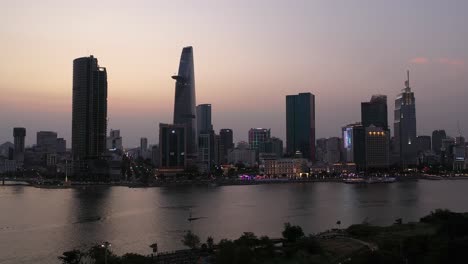 Ho-Chi-Minh-City,-Vietnam-Skyline-and-Saigon-river-waterfront-aerial-panorama-on-a-busy-evening-featuring-all-key-buildings-illuminated-against-beautiful-colored-sky
