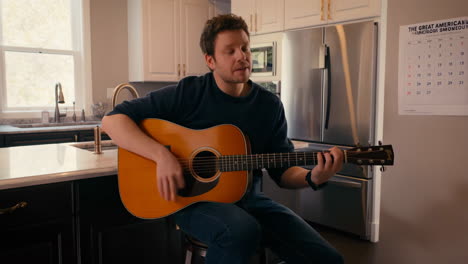 Man playing guitar in kitchen