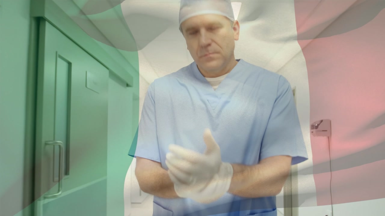 Animation of flag of italy over caucasian male doctor walking