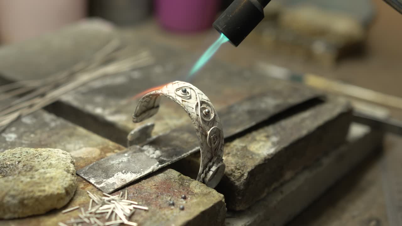 Gioielliere al lavoro in gioielleria. Banco da lavoro per la creazione di gioielli artigianali con strumenti professionali. Primo piano degli strumenti. Thailandia.