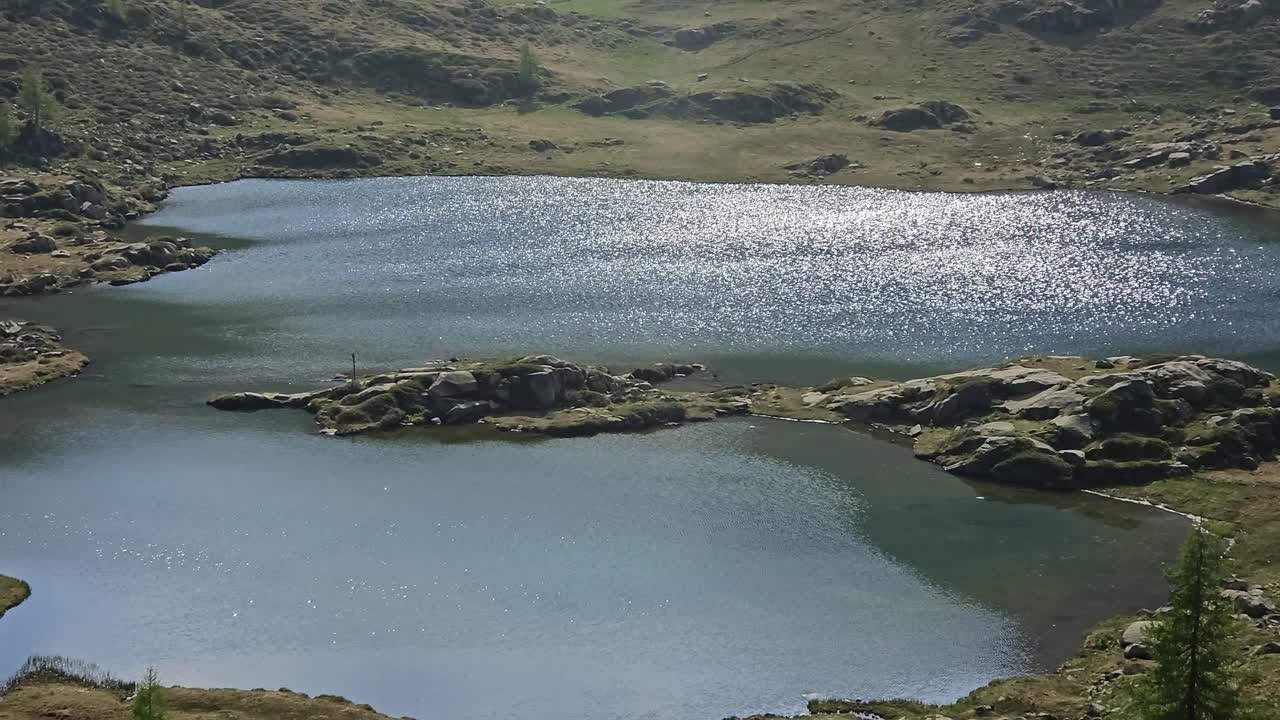 İtalyan Dolomitleri'ndeki Lago Juribrutto Gölü'nün yüzeyinde parıldayan güneş ışınları.