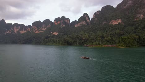 4k drone video alongside a boat sailing around khao sok national park in thailand