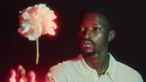 fascinated man watching flower levitating and glowing with red light