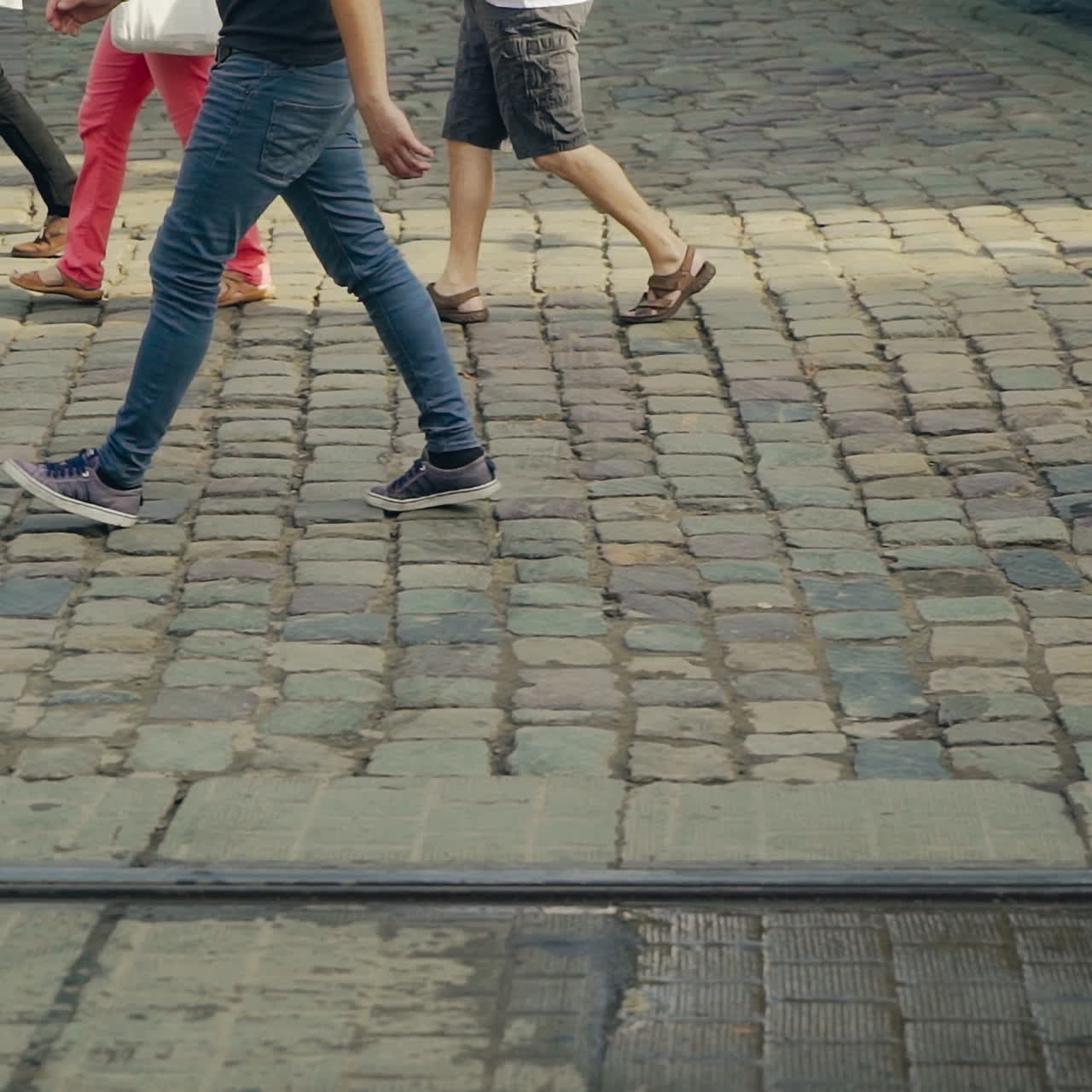 Pedestrians crossing the main street on the old pavement in Lviv. Movement of people's legs on the road in ancient city after the rain.
