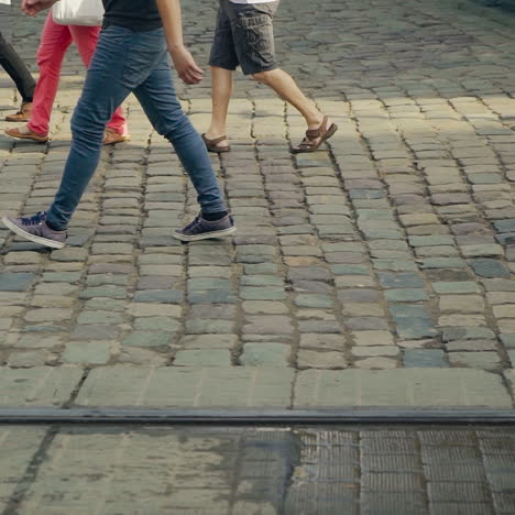 pedestrians crossing the main street on the old pavement in lviv. movement of people's legs on the road in ancient city after the rain.