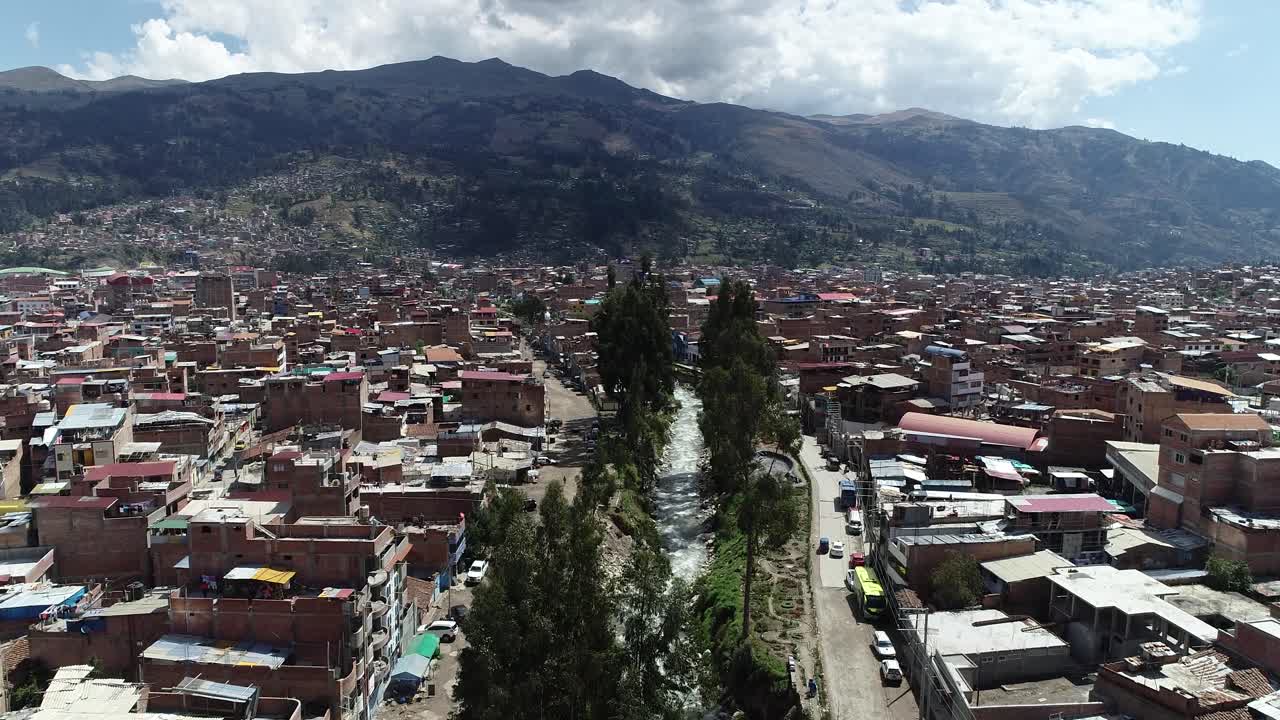 Drone shot of Huaraz, Peru, capturing its dense urban layout with a river cutting through the city, framed by Andean mountains. Ideal for urban, cultural, and environmental projects."